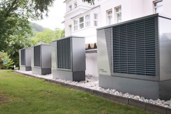 Row of heat pumps outside a building promoting sustainable energy solutions.