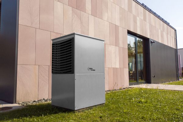 A modern heat pump unit installed outdoors next to a contemporary building, showcasing renewable energy technology.